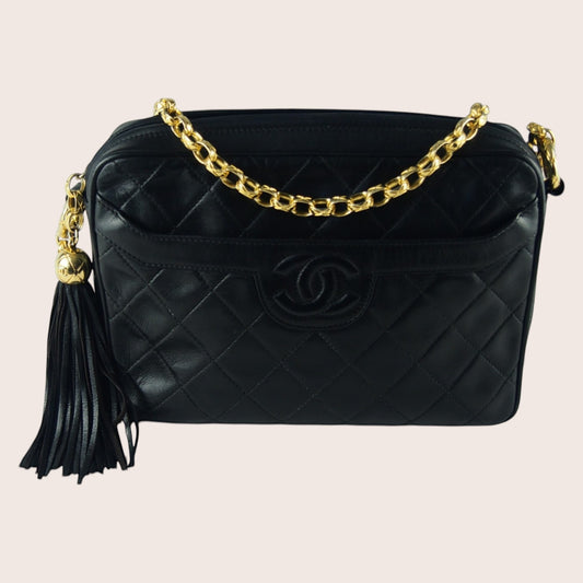 Schwarze Chanel Vintage Camera Bag aus Lammleder mit Rautensteppung, goldener Kette und dekorativem Quastenanhänger.