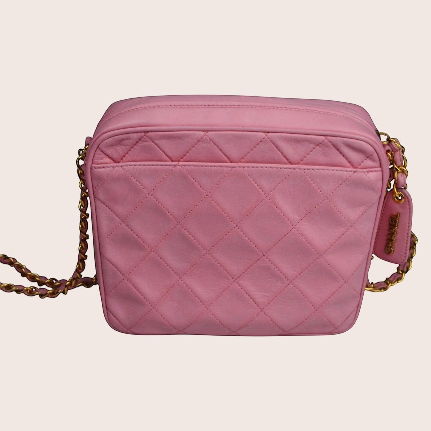 Nandalee pink quilted lambskin Chanel camera bag with gold chain strap and tassel detail.
