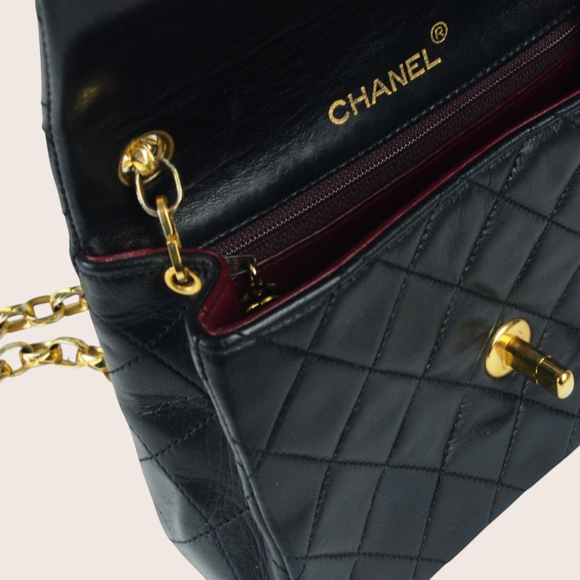 Innenansicht der Chanel Mini Bijoux Tasche mit geprägtem Chanel-Logo im bordeauxfarbenen Lederfutter.