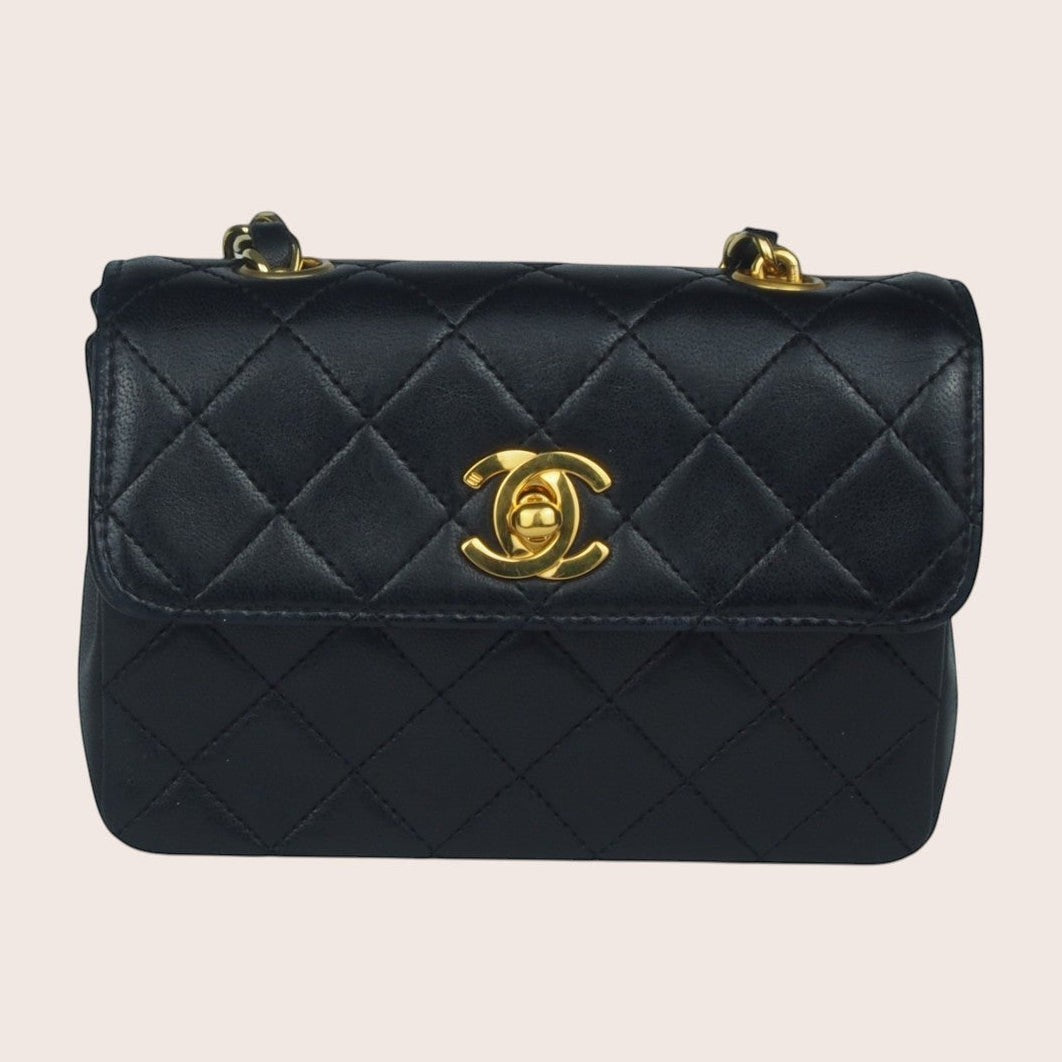 Schwarze Chanel Mini Tasche aus gestepptem Leder mit goldfarbenem CC-Verschluss, Frontansicht.