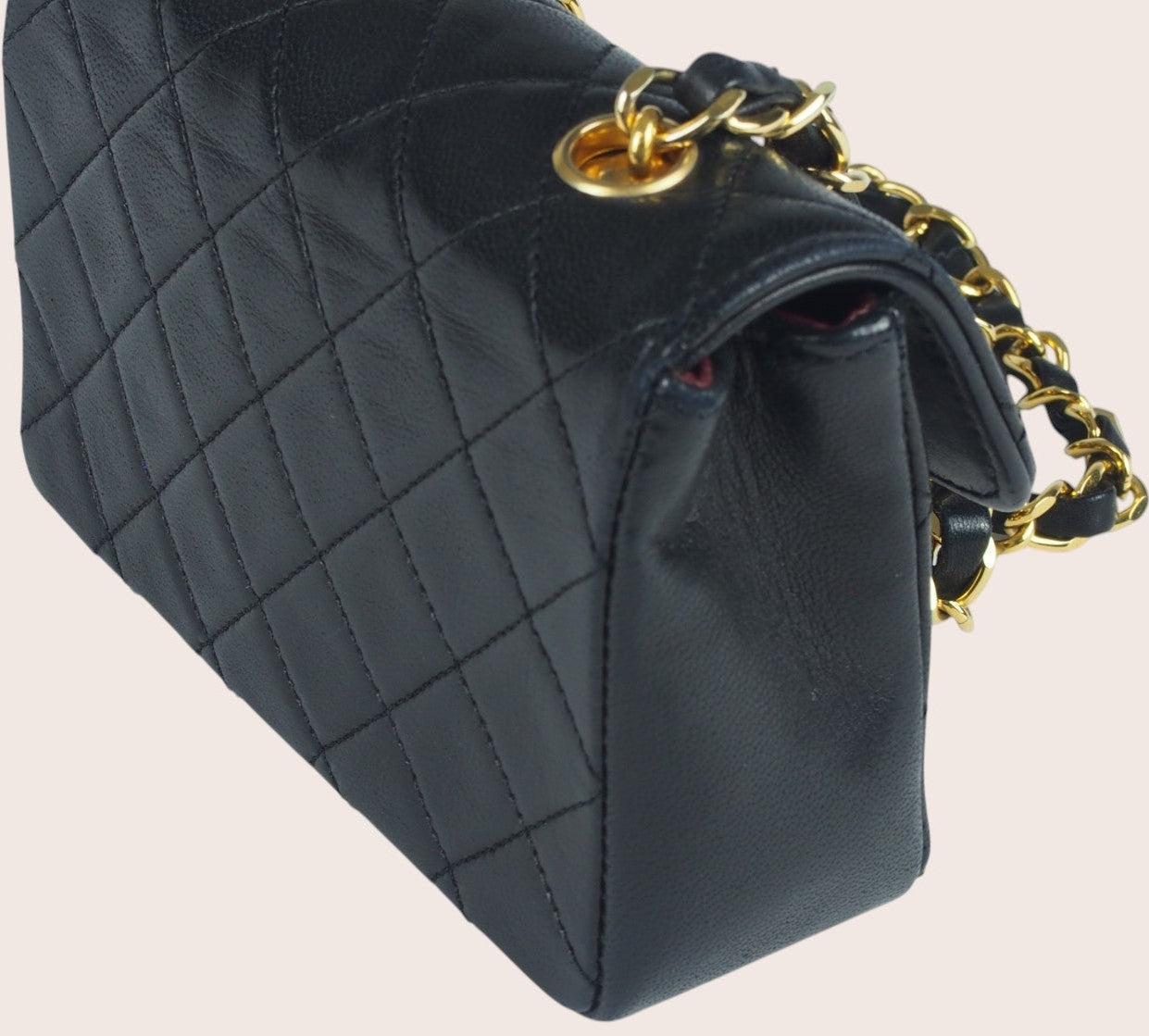 Schräge linke Seitenansicht der schwarzen Chanel Mini Tasche aus gestepptem Leder.