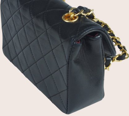 Schräge linke Seitenansicht der schwarzen Chanel Mini Tasche aus gestepptem Leder.