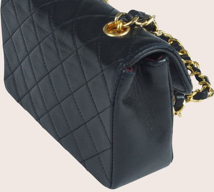 Schräge linke Seitenansicht der schwarzen Chanel Mini Tasche aus gestepptem Leder.