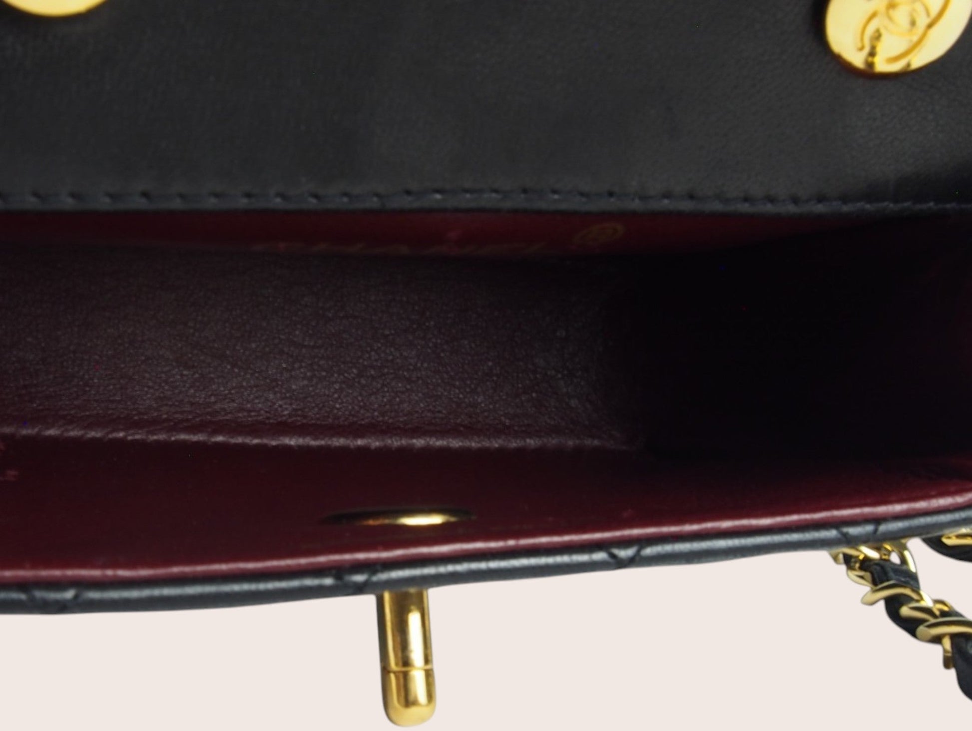 Innenraum der schwarzen Chanel Mini Tasche mit bordeauxfarbenem Lederfutter.
