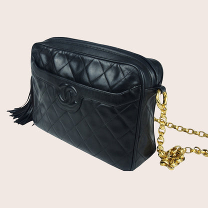 Nandalee black lambskin Chanel Single Flap vintage camera bag with gold chain and tassel detail.