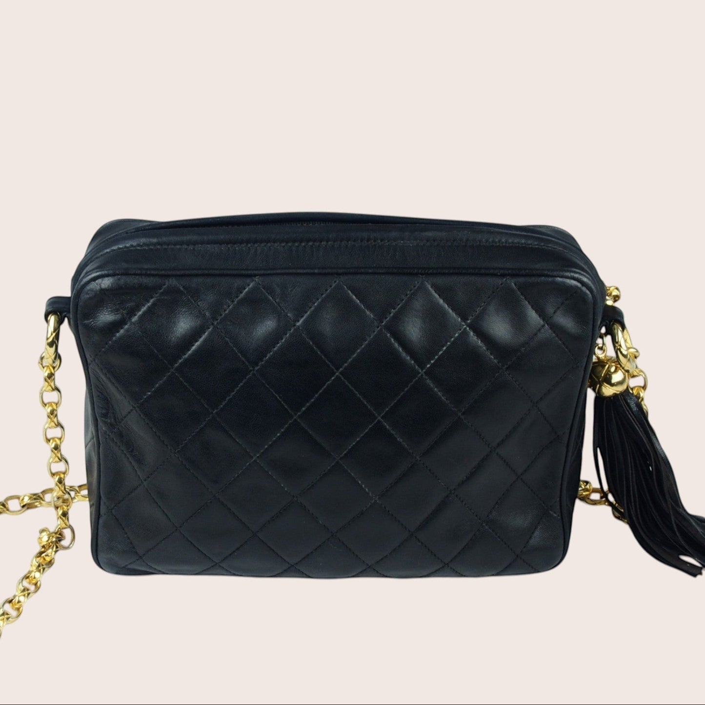 Nandalee black lambskin Chanel Single Flap vintage camera bag with gold chain and tassel detail.