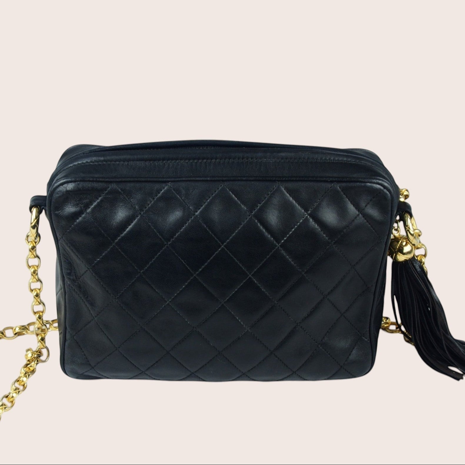 Nandalee black lambskin Chanel Single Flap vintage camera bag with gold chain and tassel detail.