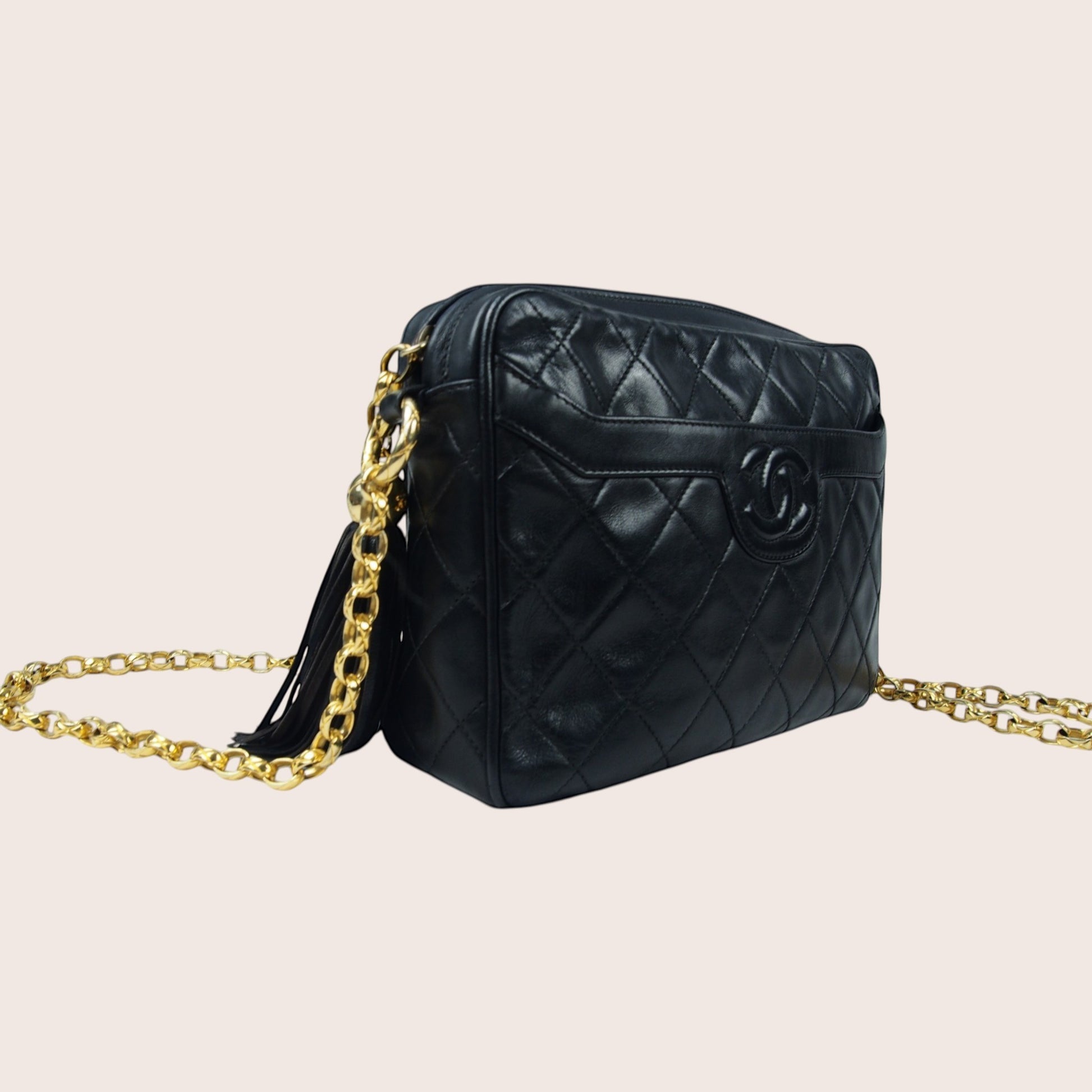Nandalee black lambskin vintage Chanel single flap camera bag with gold chain strap and tassel.