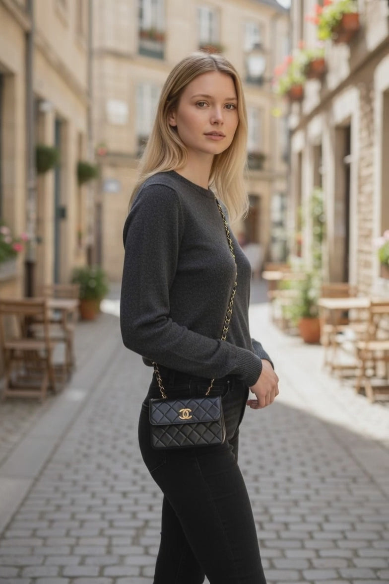 Schwarze Chanel Mini Tasche crossbody getragen mit goldfarbenem Kettenriemen.